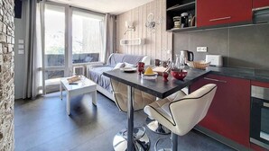 A modern kitchen with red cabinets, a dining area with a table and chairs, and a large window with curtains. - Ski-in/ski-out & foot of the slopes, 5th floor, balcony, tv, 27m², Les Menuires (Les Menuires)