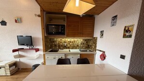 A compact kitchen with a microwave, sink, and a dining area with a table and chairs. - 150m from ski slopes, 2nd floor, view ski slopes, balcony, tv, ski locker, 24m², Les Saisies (Les Saisies)