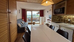 A compact kitchen with a dining area, a sofa, and a view of the outdoors. - 150m from ski slopes, 2nd floor, view ski slopes, balcony, tv, ski locker, 24m², Les Saisies (Les Saisies)