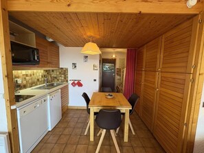 A compact kitchen with a dining area, wooden cabinets, and a tiled floor. - 150m from ski slopes, 2nd floor, view ski slopes, balcony, tv, ski locker, 24m², Les Saisies (Les Saisies)