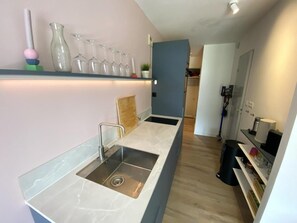 Eine moderne Küche mit Marmorarbeitsplatte, einer Spüle und einer integrierten Regalabteilung mit Gläsern.