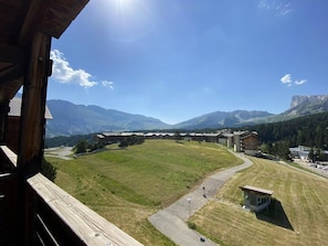 Blick auf ein Gebäude vor einer weiten, offenen Landschaft, umgeben von Bergen.