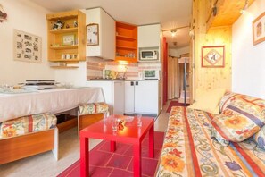 Un salon confortable avec un canapé, une table à manger et un coin cuisine équipé d’un four à micro-ondes.