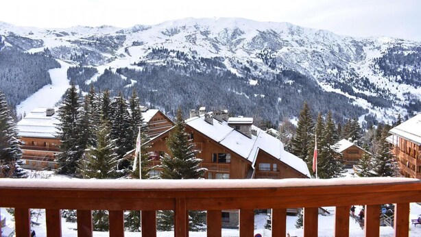 Un paysage montagneux enneigé, avec des chalets en bois et un télésiège en arrière-plan.