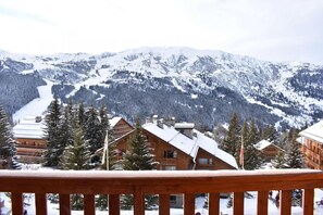 Eine verschneite Berglandschaft mit Holzhütten und einer Seilbahn im Hintergrund.