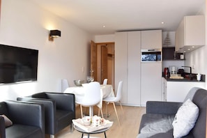 A modern living room with a TV, a dining area with a table and chairs, and a kitchen with a coffee machine. - 20m from shops, 3rd floor, view mountain, tv, 28m², Méribel (Méribel - Les Allues)
