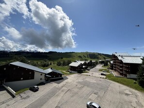 A rural hotel with a parking lot, buildings with sloped roofs, and a mountainous backdrop.