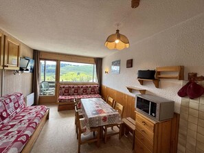 A cozy room with a sofa, a dining table, and a kitchen area including a microwave.