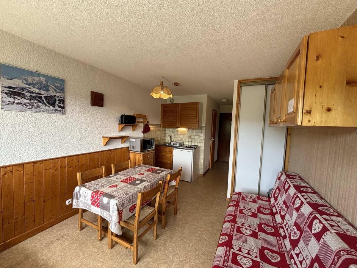 Une cuisine compacte avec des meubles en bois, une table à manger avec des chaises et un petit réfrigérateur.