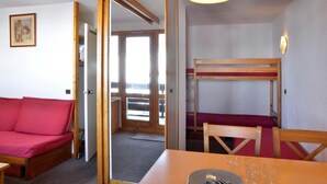 A room with a bunk bed, a red sofa, a dining table with chairs, and two pendant lights. - 100m from ski slopes, 1st floor, balcony, tv, 23m², La Plagne (La Plagne)