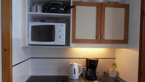 A compact kitchen with a microwave, a kettle, a coffee maker, and a sink. - 100m from ski slopes, 1st floor, balcony, tv, 23m², La Plagne (La Plagne)