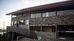 Un edificio de dos pisos con fachada de piedra y terraza de madera.