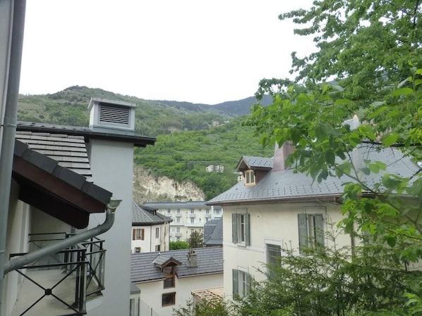Un barrio residencial con casas, una chimenea visible y una colina al fondo.