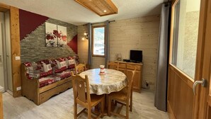 Ein gemütliches Zimmer mit einer hölzernen Bank, einem runden Tisch und einem Fernseher.