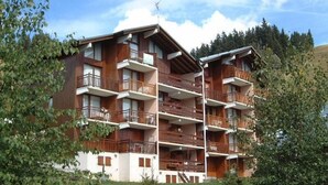 Un immeuble à plusieurs étages doté de balcons, entouré de verdure.