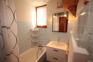 A bathroom with a bathtub, a sink, and a mirror. There are shelves above the sink and a window above the bathtub. - 100m from shops, Ground floor, view ski slopes, terrace, tv, ski locker, 23m², Les Saisies (Les Saisies)
