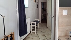 Un pasillo estrecho con un radiador blanco, una mesita con un mantel azul y una puerta que da a otra habitación.