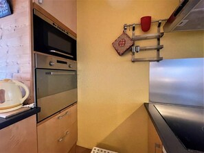 A kitchen with stainless steel appliances, wooden cabinets, and a kettle on the counter. - 10m from ski slopes, 3rd floor, balcony, tv, 36m², Les Menuires (Les Menuires)