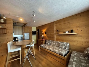 A cozy cabin interior with a wooden dining table, a sofa, and a chair.