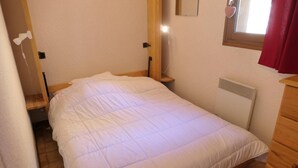 A small, single-bed room with a wooden headboard, a bedside table, and a radiator. - Ground floor, balcony, parking, tv, 23m², Saint Gervais (Saint-Gervais-les-Bains)