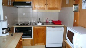Una cocina compacta con armarios de madera, estufa, lavavajillas y microondas.