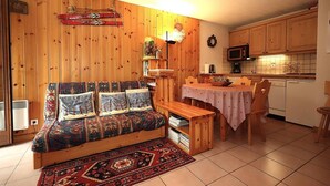A cozy room with a wooden bed, a small dining table, and a kitchen area.