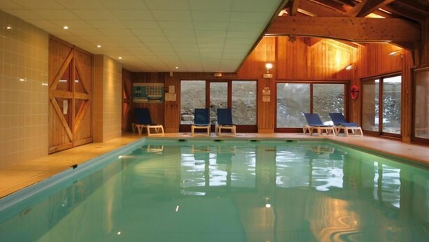 An indoor swimming pool with wooden walls and large windows.