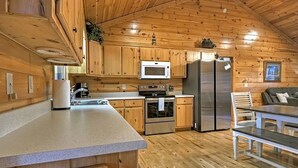 Cocina tipo cabaña de madera con una isla central, electrodomésticos de acero inoxidable y un comedor con banco.
