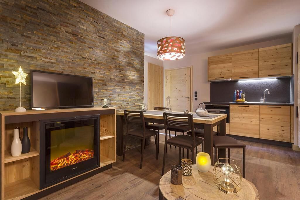 Una sala de estar moderna con chimenea, televisor, comedor y cocina.