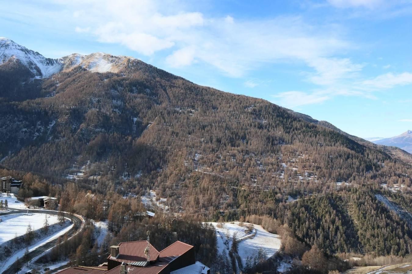 Eine gebirgige Landschaft, in der ein Dorf im Tal liegt.