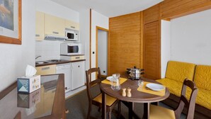Una cocina compacta con electrodomésticos modernos, una mesa de comedor con un mantel individual amarillo y un sofá con cojines amarillos.