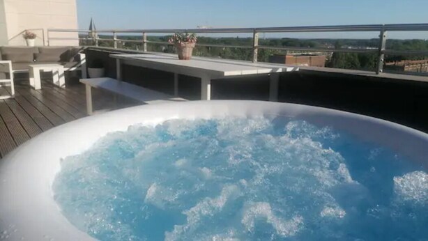 Una vasca idromassaggio su un pontile di legno con vista sulla città.
