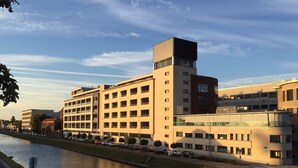 Un edificio moderno con diversi piani, un cortile centrale e un fiume in primo piano.