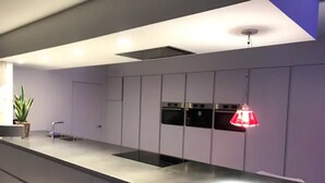 Una cucina moderna con un piano di lavoro lungo, elettrodomestici integrati e una lampada a sospensione.