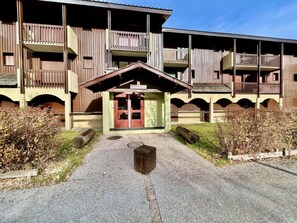 A building with a central entrance, multiple balconies, and a small porch area.