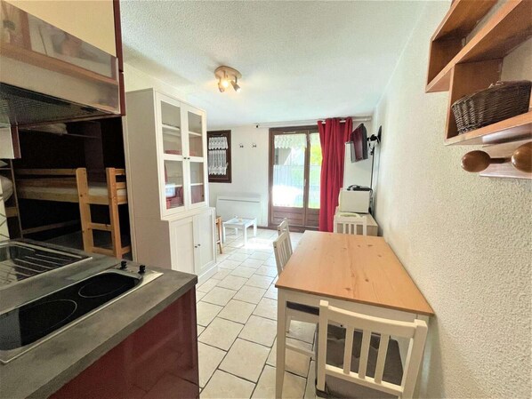 A compact kitchen with a stove, cabinets, and a dining area with a table and chairs.