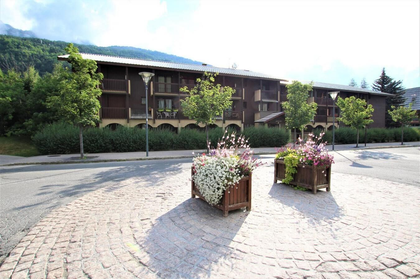 Un hotel dallo stile architettonico tradizionale, con un cortile centrale decorato da fioriere e un percorso pedonale lastricato.