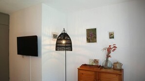 Une pièce comprenant une commode en bois, un lampadaire et un téléviseur à écran plat fixé au mur.