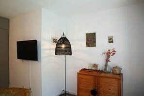 Relax in a serene space with a flat-screen TV, floor lamp, and comfortable dresser.