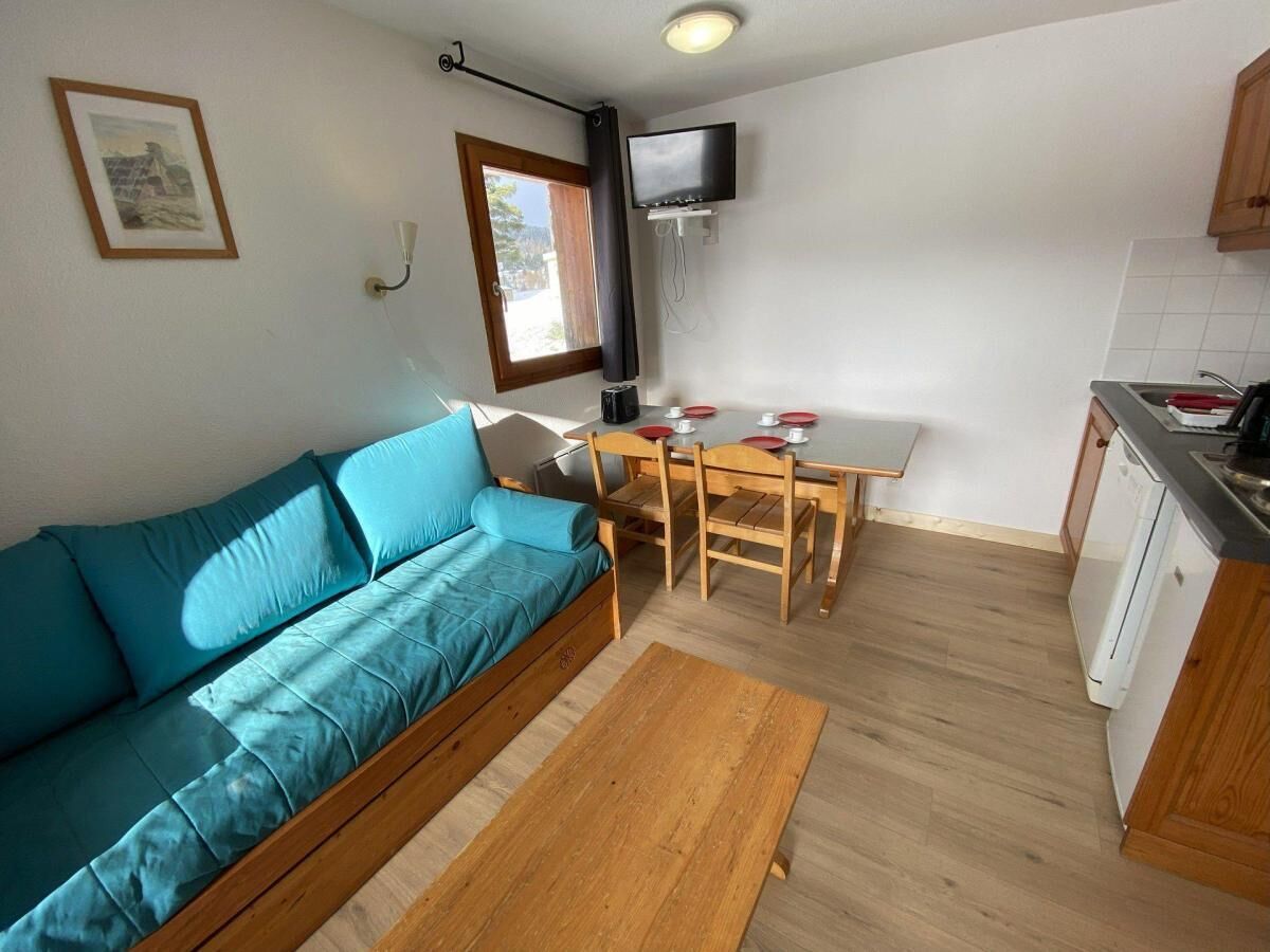 Un espacio habitable compacto con sofá, mesa de comedor y zona de cocina.