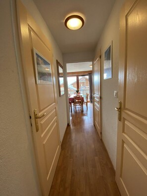 A hallway with wooden flooring, white doors, and a ceiling light. - 1st floor, view mountain, balcony, tv, 32m², La Joue du Loup (Le Dévoluy)