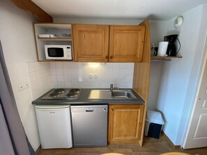 A compact kitchen with a microwave, stove, sink, and dishwasher.