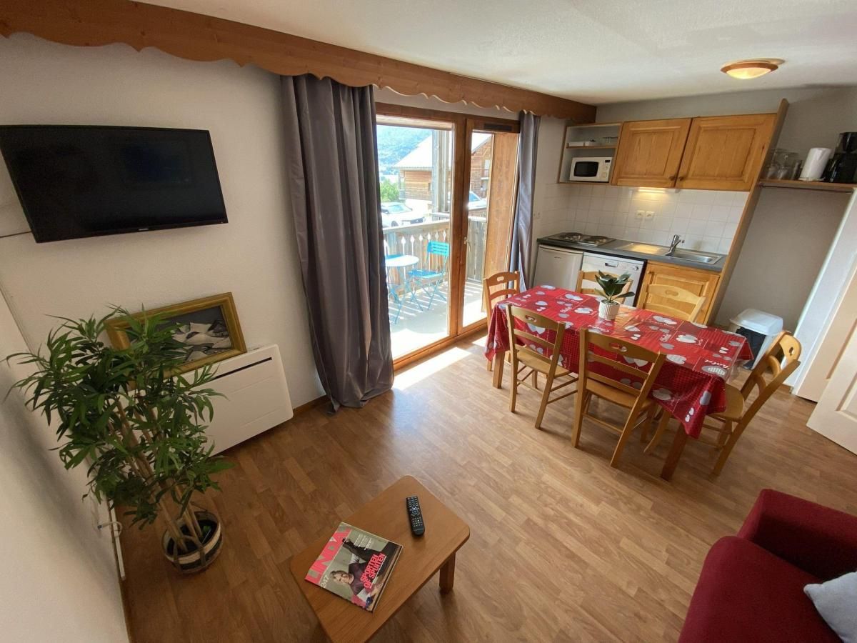 A compact living space with a dining area, kitchenette, and a television mounted on the wall.