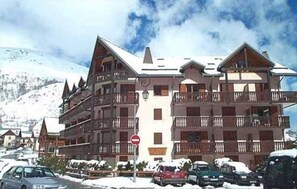 A multi-story hotel with balconies, a ski resort in the background, and a clear sky. - 50m from ski slopes, 2nd floor, balcony, tv, ski locker, 35m², Valloire (Valloire)