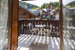 A balcony with a wooden fence, a small round table, and two folding chairs. - 50m from ski slopes, 2nd floor, balcony, tv, ski locker, 35m², Valloire (Valloire)
