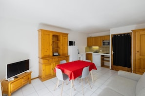 A compact living space with a dining area, kitchenette, and a television.