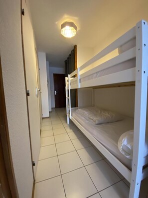A narrow hallway with two bunk beds, a door at the end, and a light fixture on the ceiling. - 50m from ski slopes, 2nd floor, balcony, tv, ski locker, 35m², Valloire (Valloire)