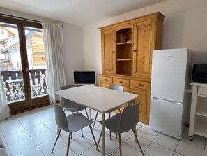 A kitchen with a white table, grey chairs, a wooden cabinet, and a white refrigerator. - 50m from ski slopes, 2nd floor, balcony, tv, ski locker, 35m², Valloire (Valloire)