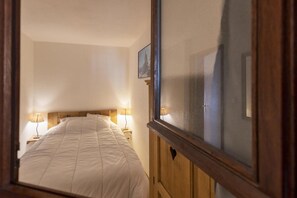 A bedroom with a bed, two bedside lamps, a wooden headboard, and a window with a view. - 50m from ski slopes, 2nd floor, balcony, tv, ski locker, 35m², Valloire (Valloire)
