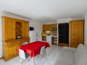 A compact living space with a kitchenette, a dining area with a red table, and a grey sofa. - 50m from ski slopes, 2nd floor, balcony, tv, ski locker, 35m², Valloire (Valloire)